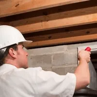 Termite inspection technician checking a basement wall and framing for termite activity in Portland, OR